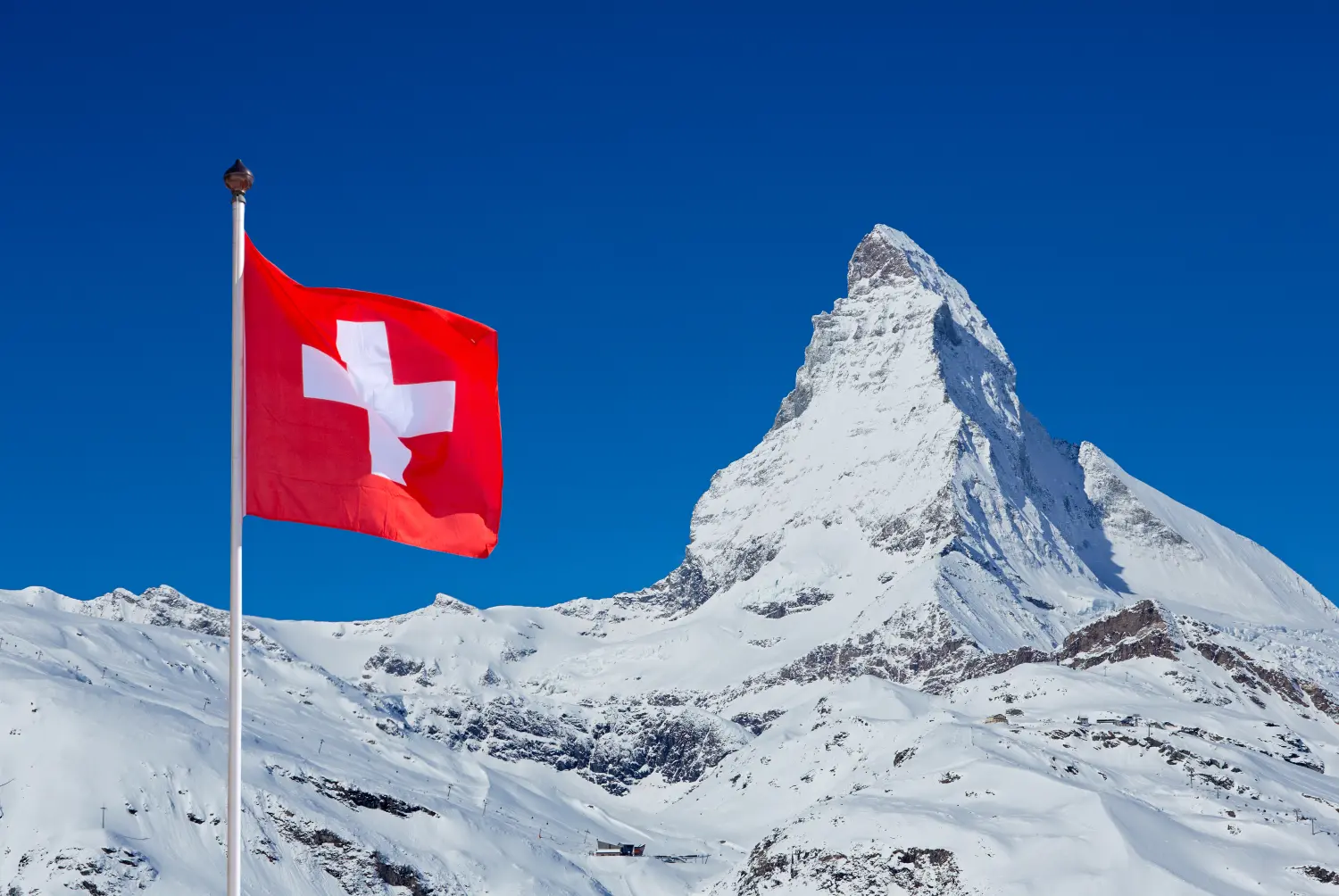 Berühmtes Matterhorn mit Schweizer Flagge am blauen Himmel